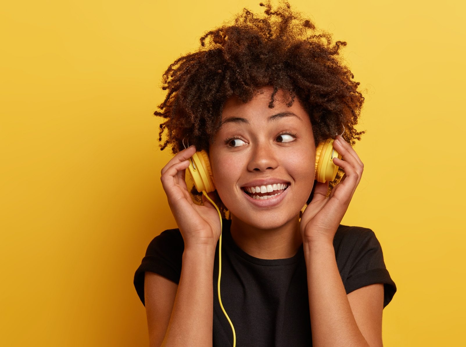 demo-attachment-36-happy-dark-skinned-woman-wears-wired-headphones-enjoys-nice-music-looks-away-has-toothy-smile