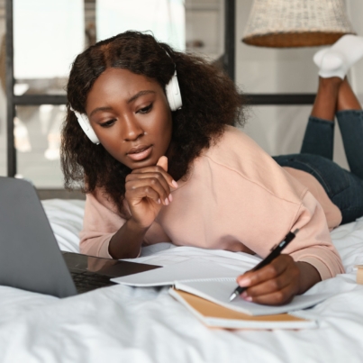 Black Woman Learning Using Laptop Taking Notes At Home